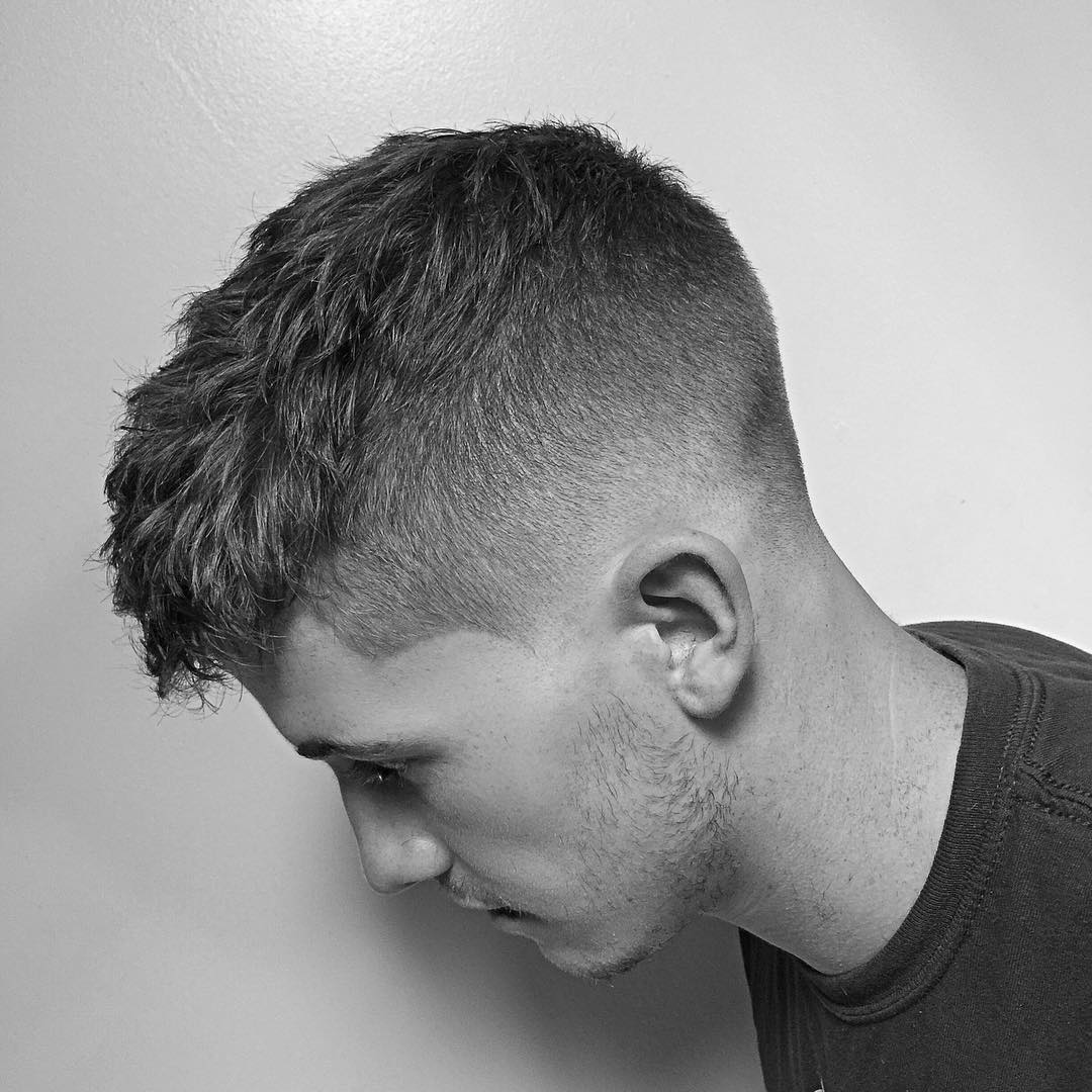 Side View Of A Head Of Stylish Smiling Bearded Man Sitting In The  Barbershop Covered With Black Peignoir Barber In Casual Clothes Standing  Behind Customer Making Boxer Haircut With Clipper And Comb