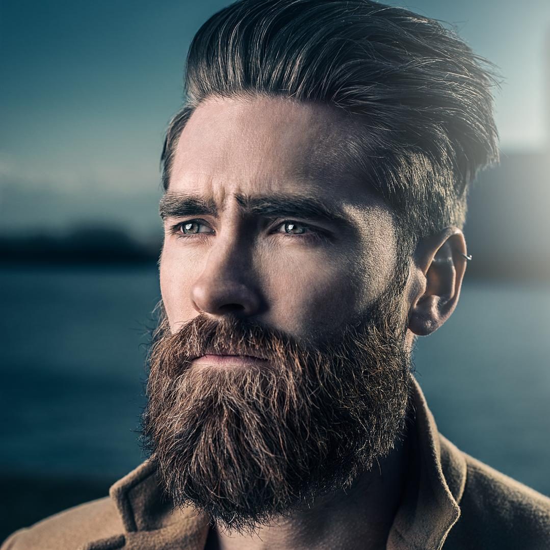 Thick hair hairstyle for men with short sides and beard.