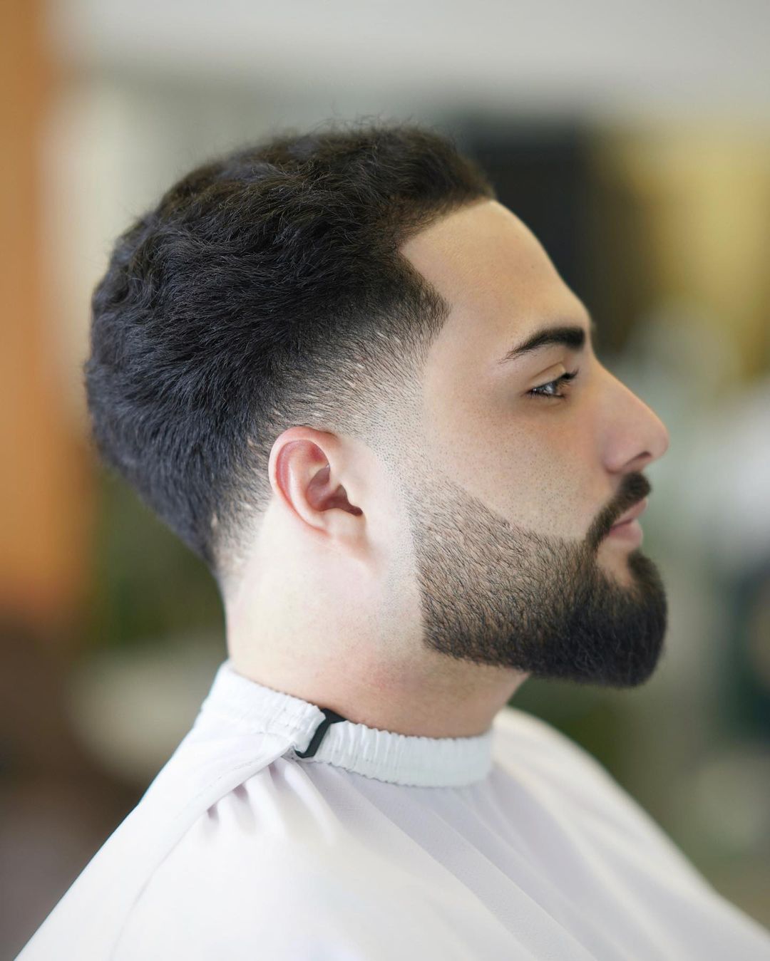 Corte de cabelo muito baixo fade com cabelo ondulado e barba